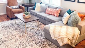 Un salon moderne comprenant un canapé, un fauteuil, une table basse et un vase décoratif.