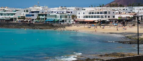 A coastal town with a beach, buildings, and a rocky shoreline.