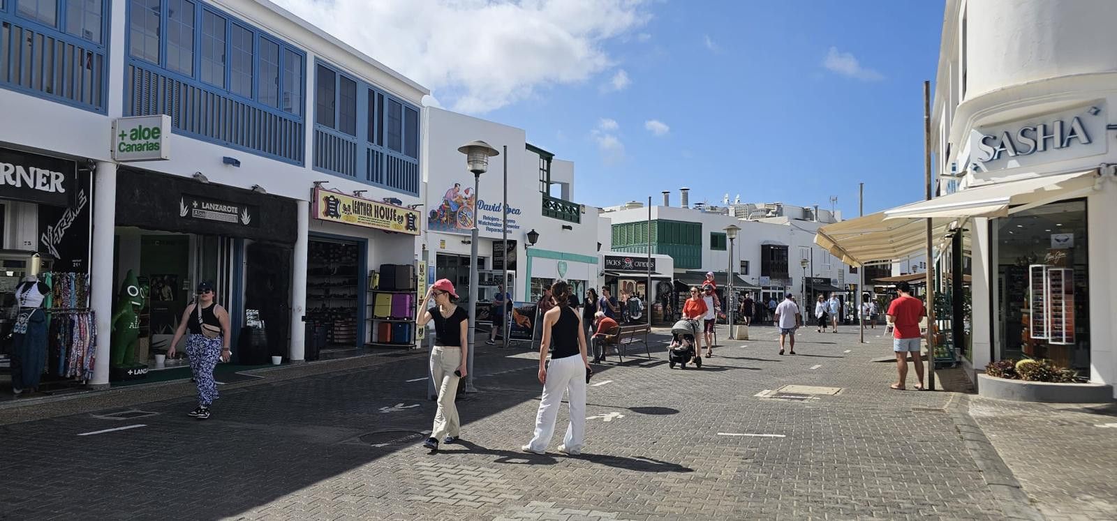 A busy pedestrian street with shops and cafes, including a visible 'Sasha' store.