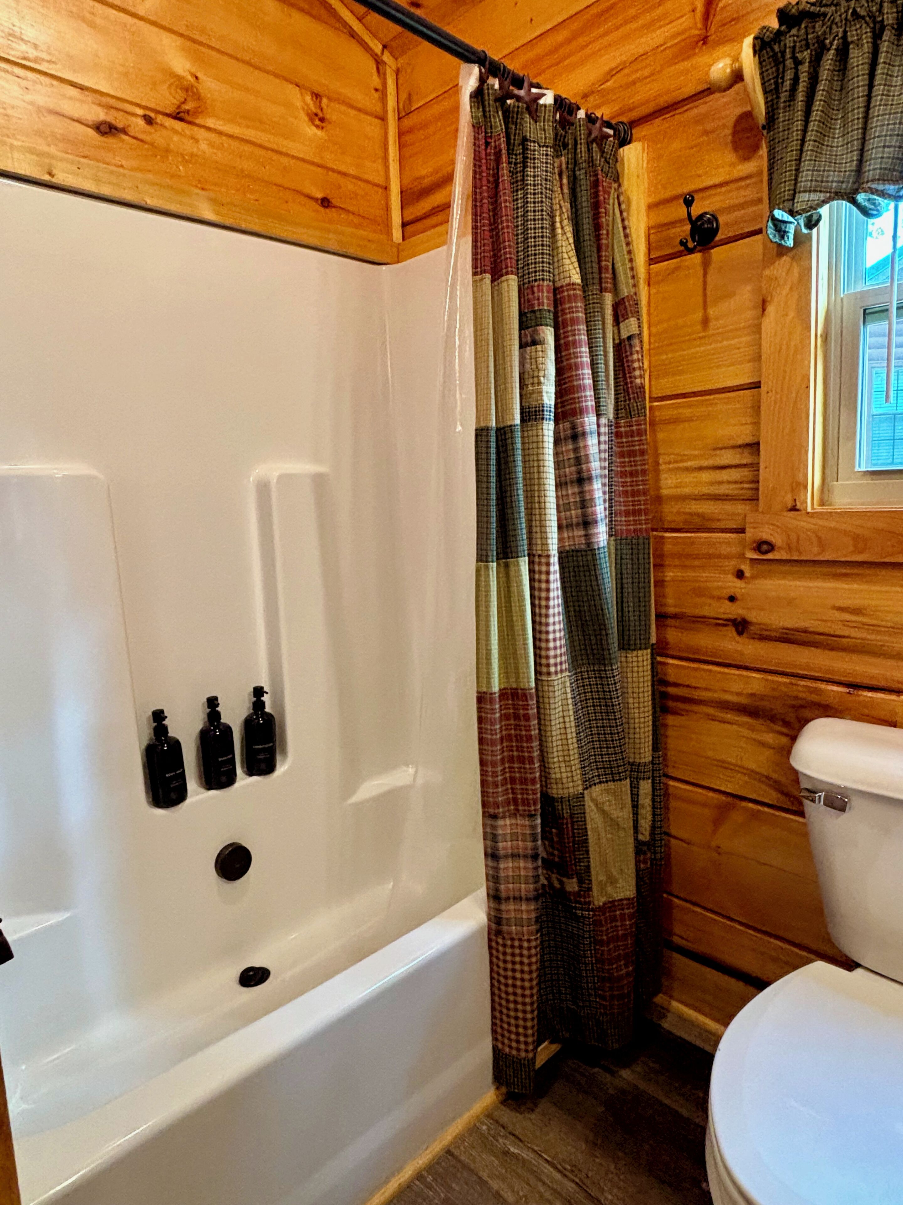 A bathroom with a white bathtub, a toilet, and a shower curtain.