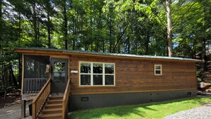 Eine kleine Holzhütte mit Veranda und einer Treppe, die zum Eingang führt.