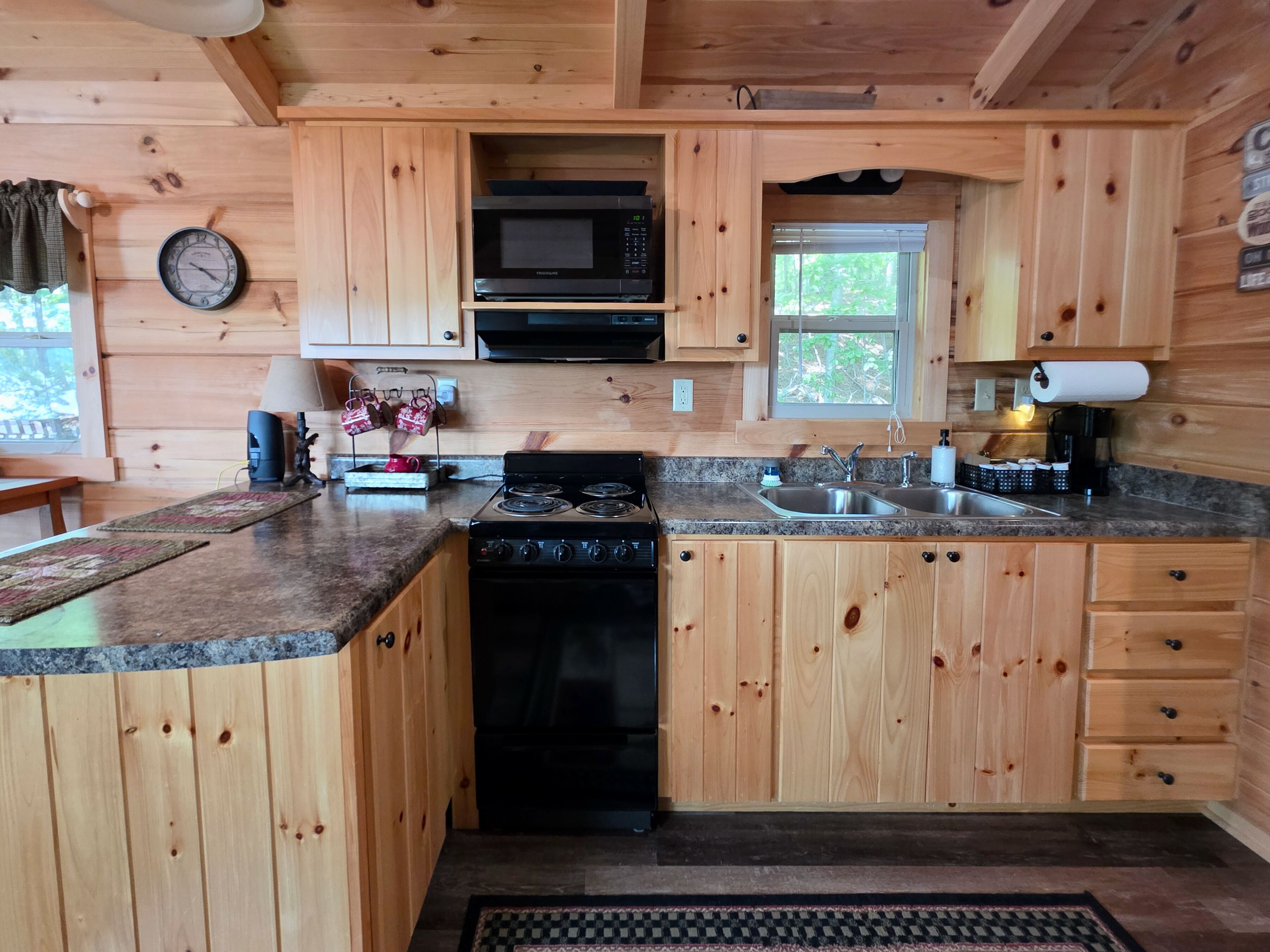 Cocina de cabaña de madera con estufa, lavamanos, microondas y armarios.