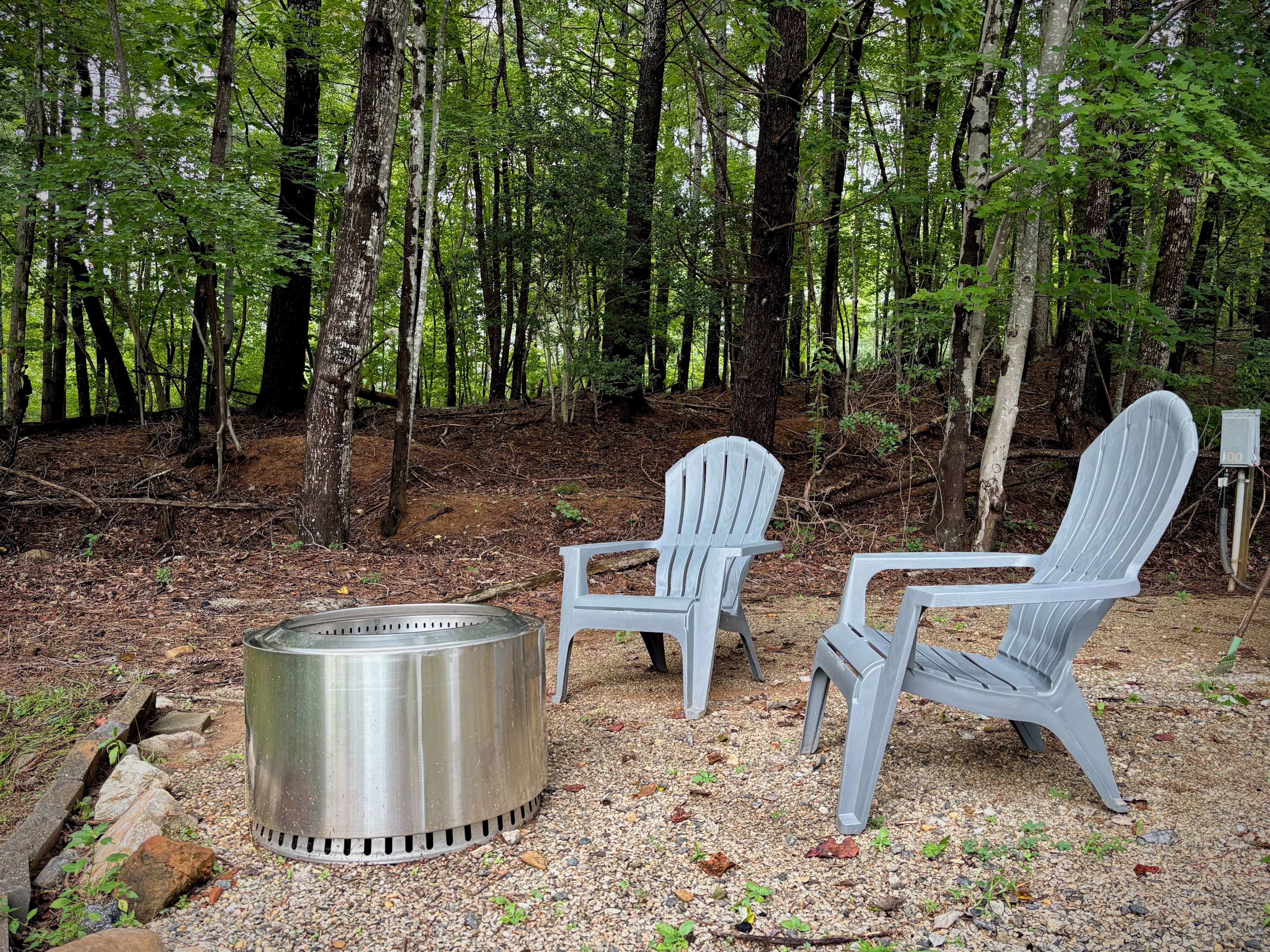 Fire pit with two Adirondack chairs at the edge of the woods for peaceful outdoor evenings