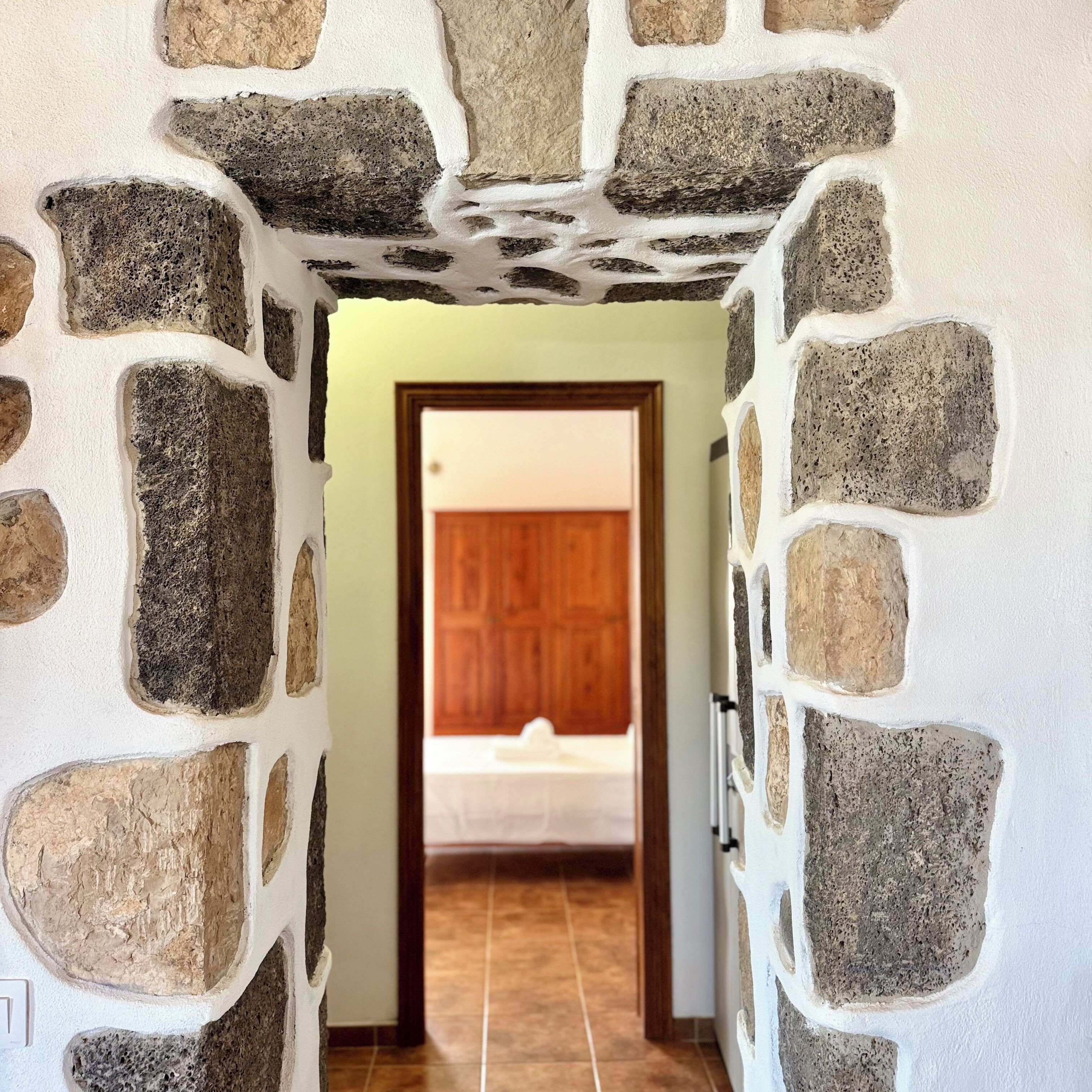 A hallway with stone walls and a wooden door leading to a room.
