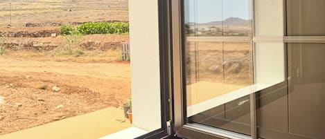 Una ventana con vistas a un paisaje árido y colinas distantes.
