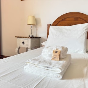 A neatly made bed with white linens, a folded towel, and a pillow. - Casa Clarita (Tindaya)