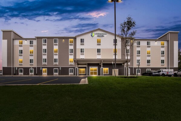 A multi-story hotel with a flat roof, a central entrance, and a parking lot in front. - Woodspring Suites St. Joseph (St. Joseph)