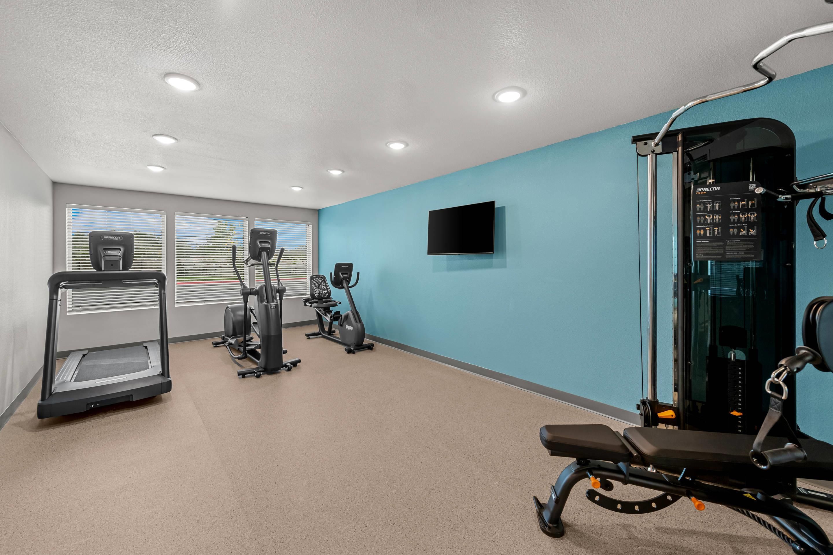 A gym with treadmills, elliptical machines, and weight equipment.