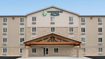 A hotel with a stone facade, multiple windows, and a central entrance with a wooden canopy.