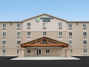 A hotel with a stone facade, multiple windows, and a central entrance with a wooden canopy.