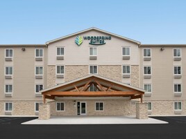 A hotel with a stone facade, multiple windows, and a central entrance with a wooden canopy.