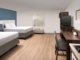 A hotel room with two beds, a desk with a chair, a television, and a window with blinds.