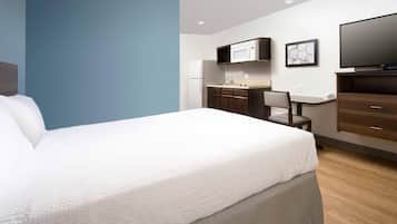 A hotel room with a bed, a desk, a chair, a television, and a microwave.