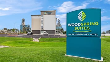 A hotel sign for WoodSpring Suites with a clear view of the building in the background.