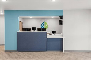 Una reception con una parete blu decorata, due monitor e un logo a parete.