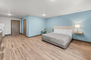 Una camera d'albergo con un letto, una scrivania, una sedia e un comodino con una lampada.