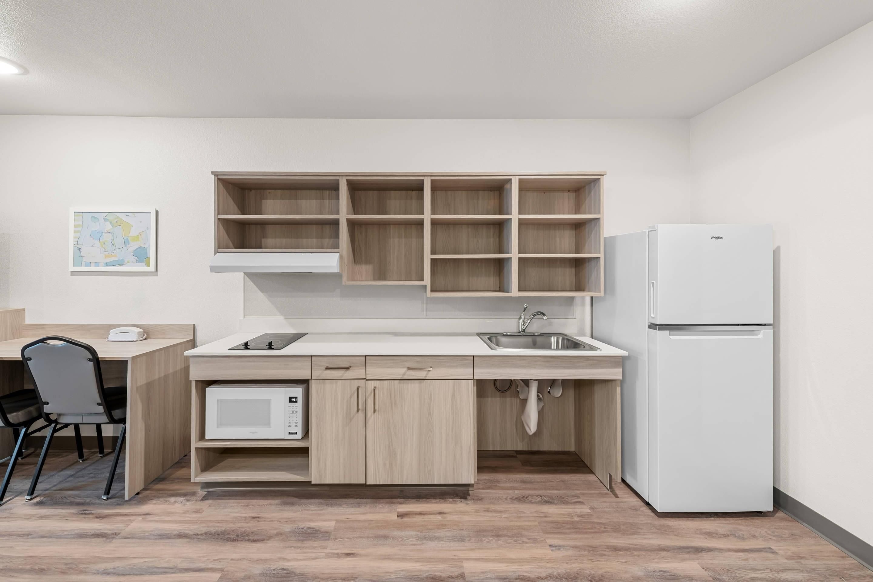 Una cocina compacta con microondas integrado, refrigerador y pileta.