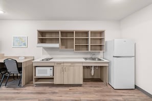 A compact kitchen with a built-in microwave, a refrigerator, and a sink. - Woodspring Suites St. Joseph (St. Joseph)