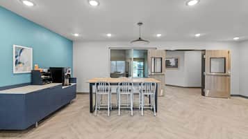 Una cocina moderna con una mesa de madera, sillas blancas y una pared de acento azul.