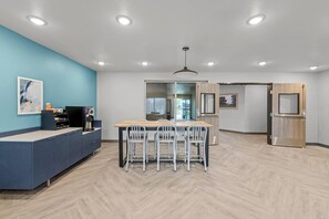 Una cocina moderna con una mesa de madera, sillas blancas y una pared de acento azul.