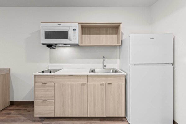 A compact kitchen with a microwave, sink, and refrigerator.
