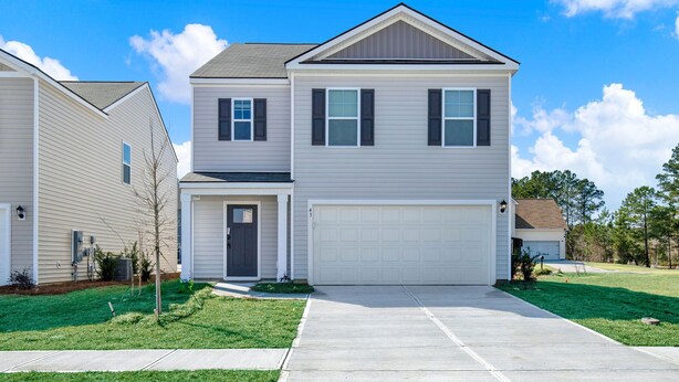 Um edifício residencial de dois andares com garagem, porta frontal e um pequeno alpendre.