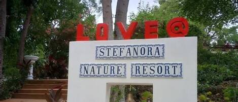 A sign for Stefaforana Nature Resort with a message about love and a bell.