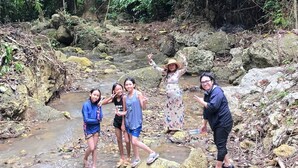 Un grupo de personas en un entorno natural, con un arroyo y rocas.