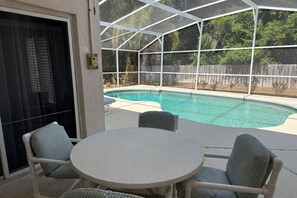Un espace extérieur abrité comprenant une piscine, des chaises et une table.