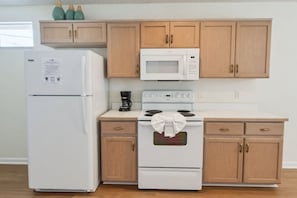 A kitchen with a refrigerator, microwave, stove, and wooden cabinets. - 3BR Pool Home in Kissimmee Sleeps 6 (Kissimmee)