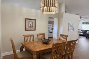 A dining area with a wooden table and chairs, a woven light fixture, and framed artwork on the walls. - 3BR Pool Home in Kissimmee Sleeps 6 (Kissimmee)