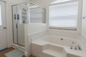 A bathroom with a glass shower enclosure, a bathtub, and a window with blinds. - 3BR Pool Home in Kissimmee Sleeps 6 (Kissimmee)