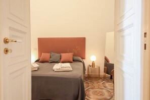 A hotel room with a bed, pillows, a bedside lamp, and a chair. - TD Palazzo Fiume 1 – Heart of Polignano (Polignano a Mare)