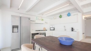 A modern kitchen with a stainless steel refrigerator, a gas stove, a microwave, and a sink. - TD Palazzo Fiume 2 – Above the Square (Polignano a Mare)