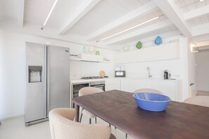 Eine moderne Küche mit einem Edelstahl-Kühlschrank, einem Gasherd, einer Mikrowelle und einem Spülbecken.