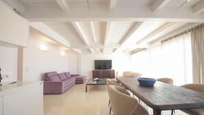A modern living room with a sofa, a coffee table, and a dining table with chairs. - TD Palazzo Fiume 2 – Above the Square (Polignano a Mare)