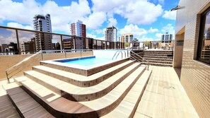Una piscina en la azotea con escalones que conducen a una vista panorámica de la ciudad.