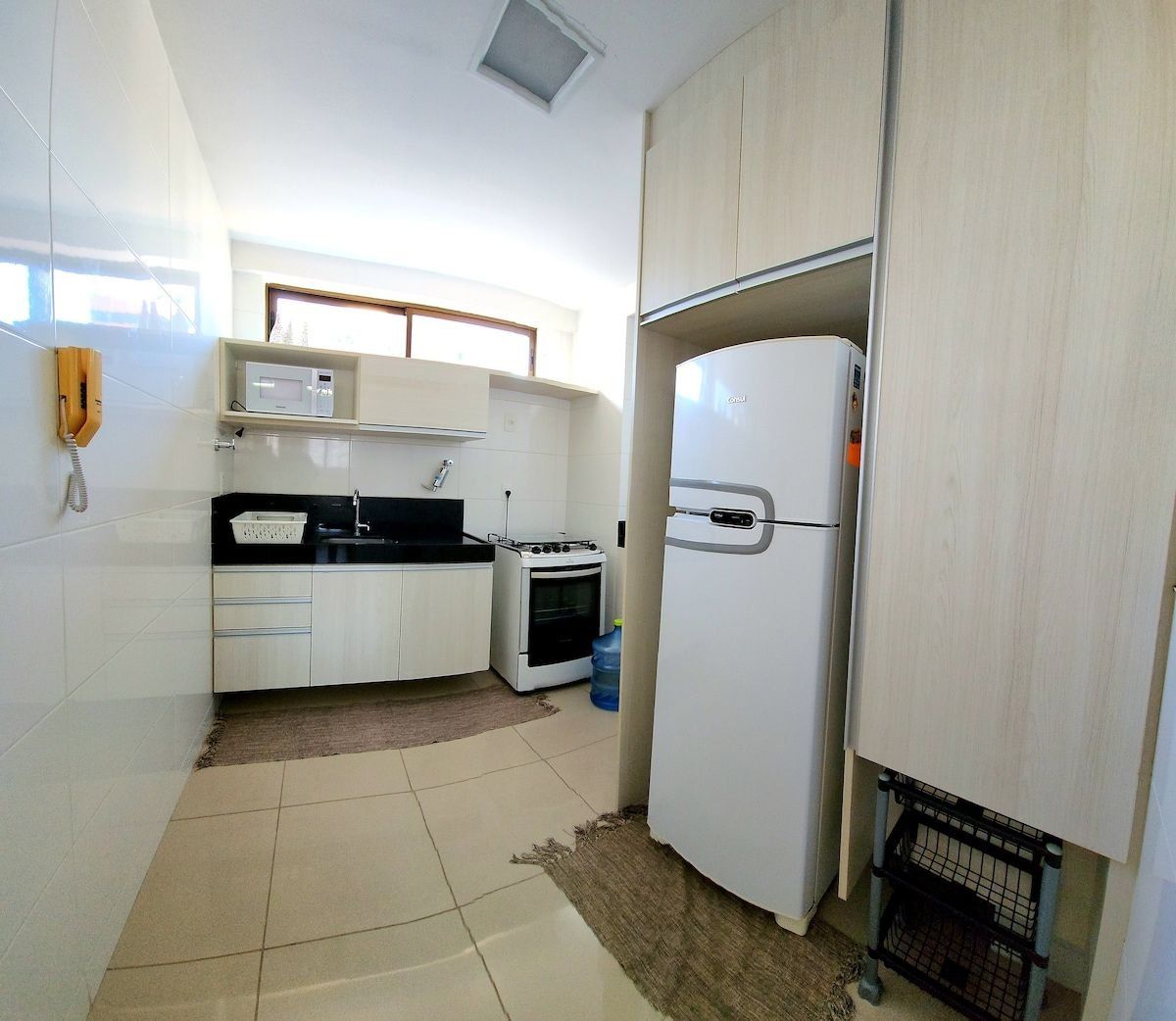 A compact kitchen with white cabinets, a stove, a refrigerator, and a microwave.