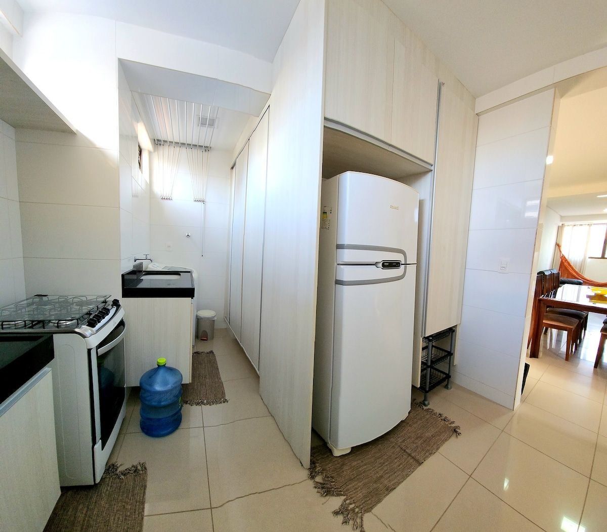 Una cocina compacta con estufa, refrigerador y un pequeño comedor con mesa y sillas.