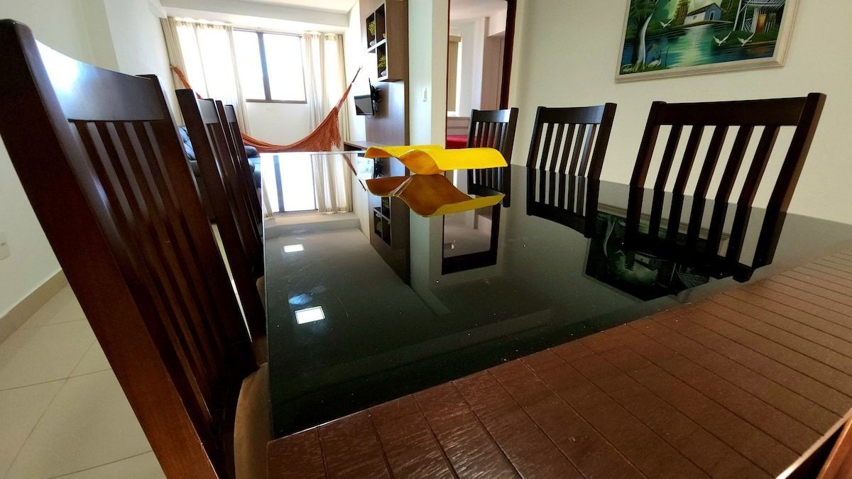 Un comedor con sillas de madera, una mesa central y una hamaca.