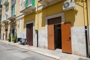 Un conjunto de edificios con balcones, una calle y un coche estacionado.