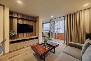 Ein modernes Wohnzimmer mit Flachbildfernseher, Holzvertäfelung, einer Couch und einer Schiebetür zu einem Balkon.