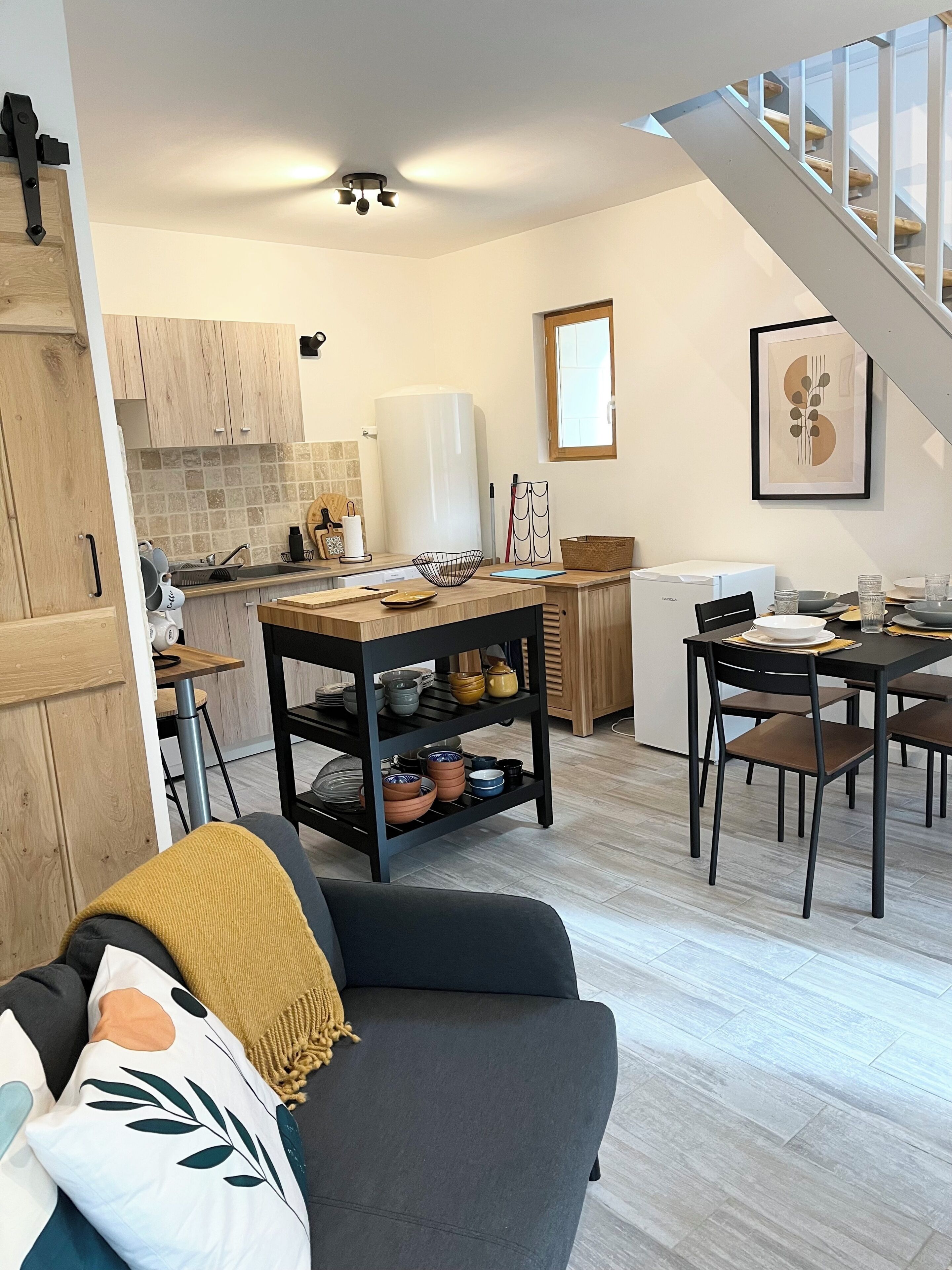 Eine moderne Küche mit Essbereich, einer Treppe und einem Wohnzimmer mit Sofa.