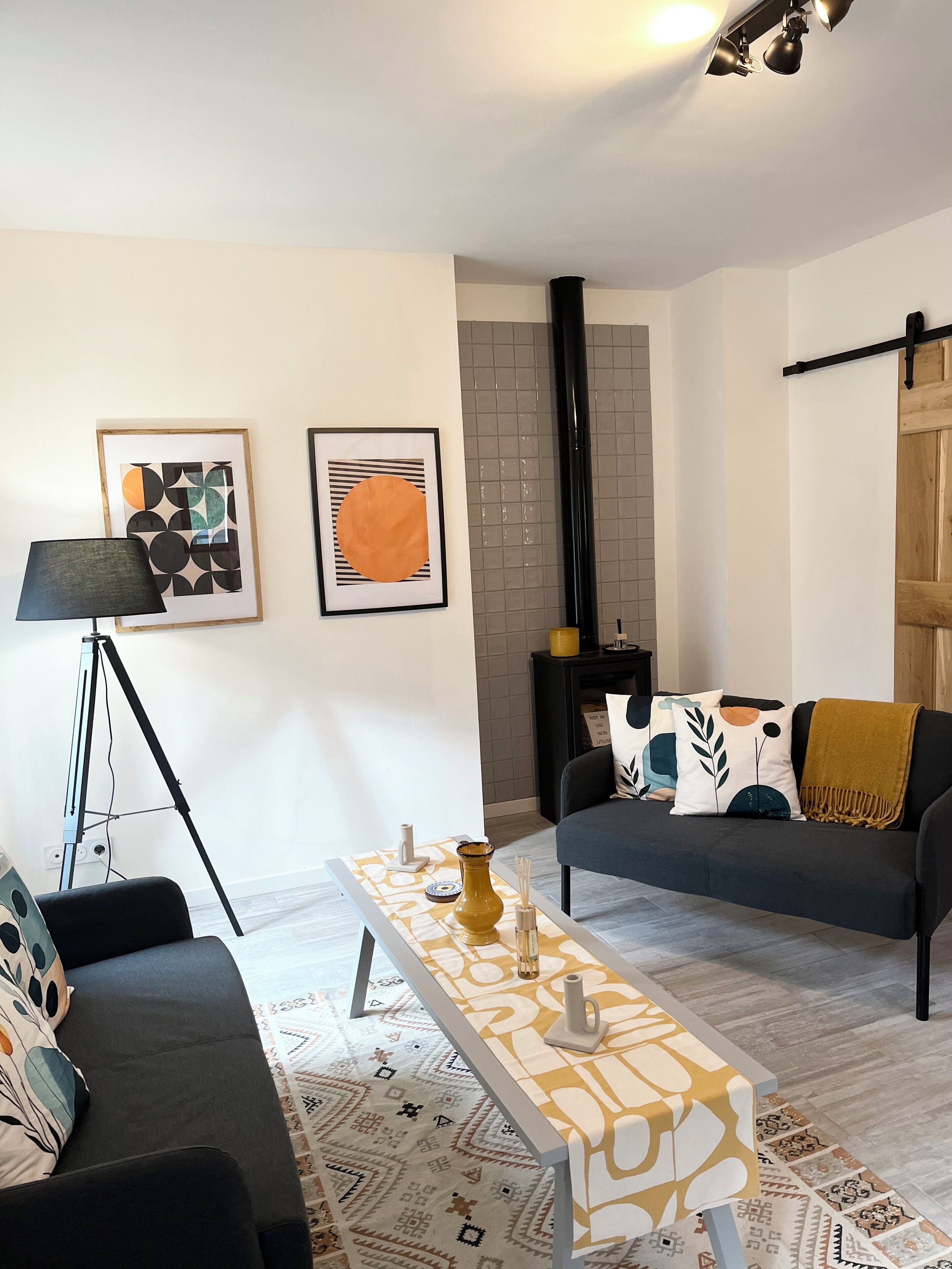 A living room with a sofa, a coffee table, a floor lamp, and two framed artworks on the wall.