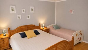 Ein Schlafzimmer mit zwei Betten, einem Holzkopfteil, Nachttischen mit Lampen und Wandbildern.