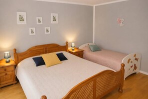 Ein Schlafzimmer mit zwei Betten, einem Holzkopfteil, Nachttischen mit Lampen und Wandbildern.