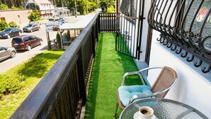 Ein Balkon mit Blick auf eine Straße, ein kleiner Tisch mit zwei Tassen und ein Stuhl.
