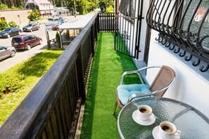 Ein Balkon mit Blick auf eine Straße, ein kleiner Tisch mit zwei Tassen und ein Stuhl.