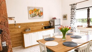 A dining area with a wooden table, white chairs, and a vase of tulips. - Holiday home for 6 people Mrzeżyno (Mrzeżyno)