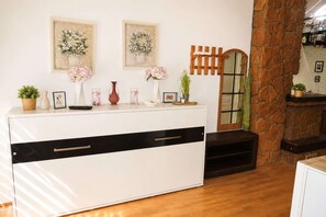 Ein Zimmer mit einer weißen Kommode, einem Spiegel und zwei gerahmten floralen Wandbildern.